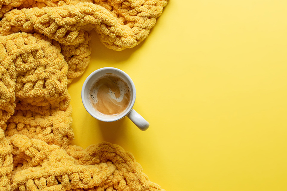 Knit Challenge header showing a yellow knitted blanket next to a cup of tea or coffee on a yellow background.